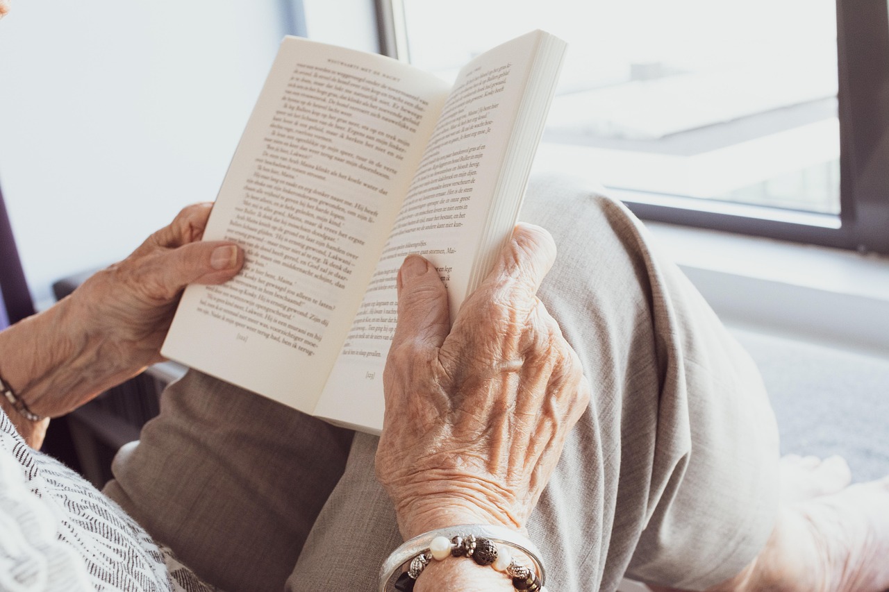 an older adults hands holding an open book
