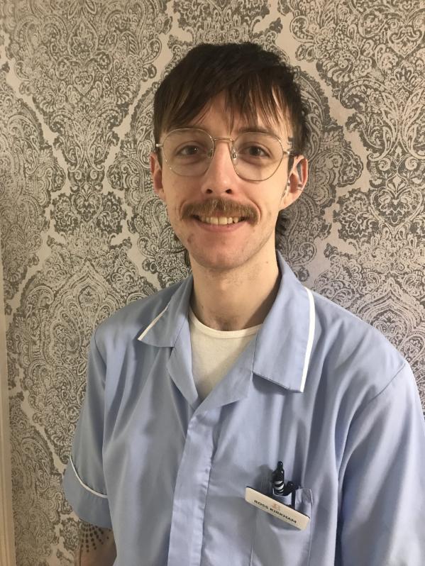 man with glasses smiling for staff photo