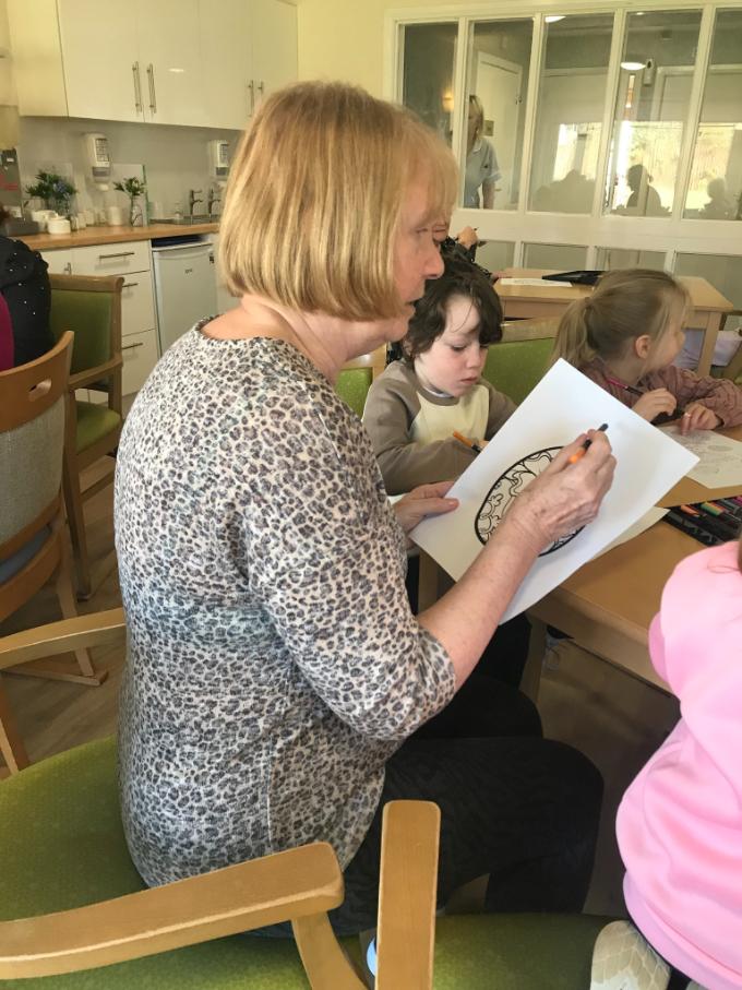older lady colouring an easter egg drawwing